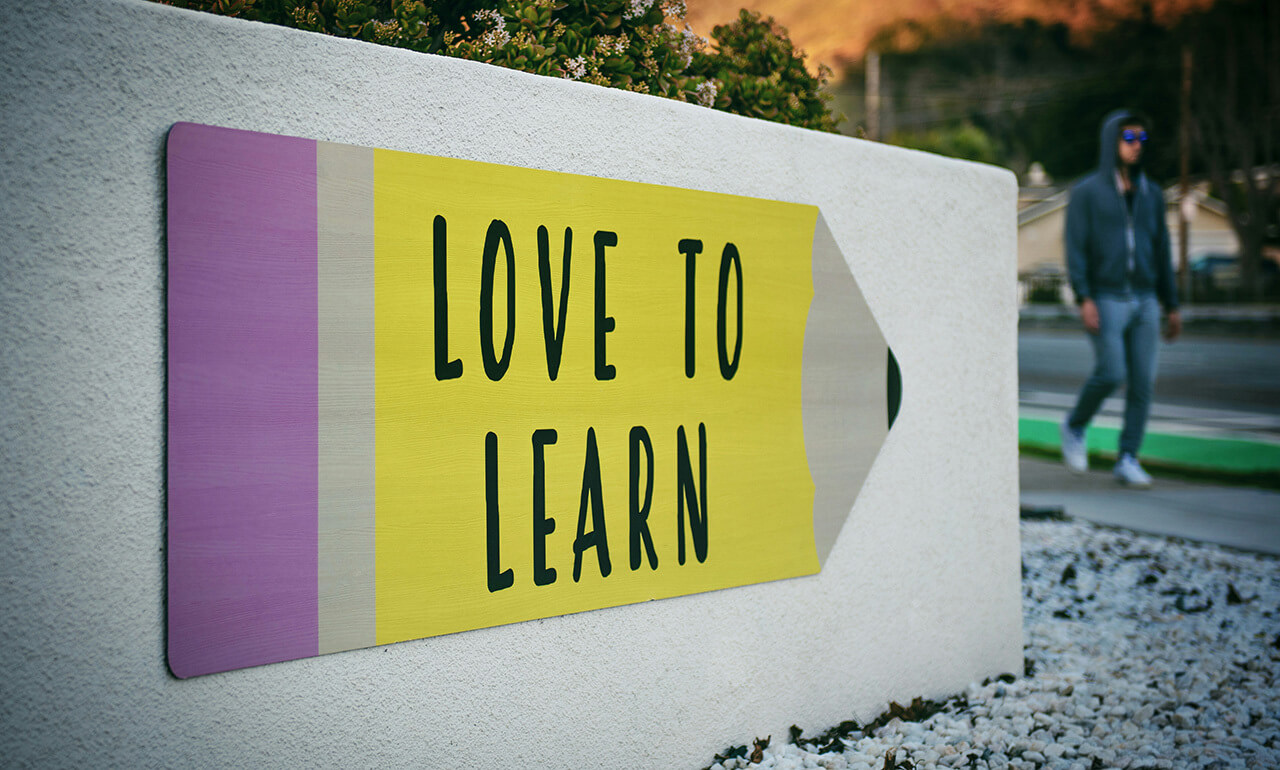 Eine Wand mit einem Schild in Bleistiftform, auf dem LOVE TO LEARN steht.